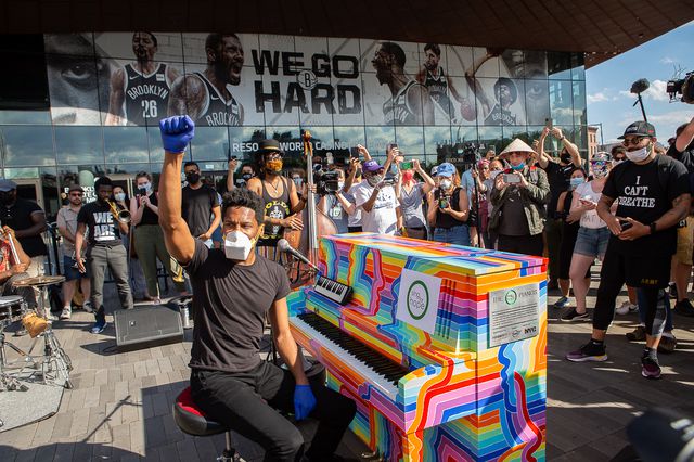 Jon Batiste with a fist raised at a protest concert outside of Barclays Center